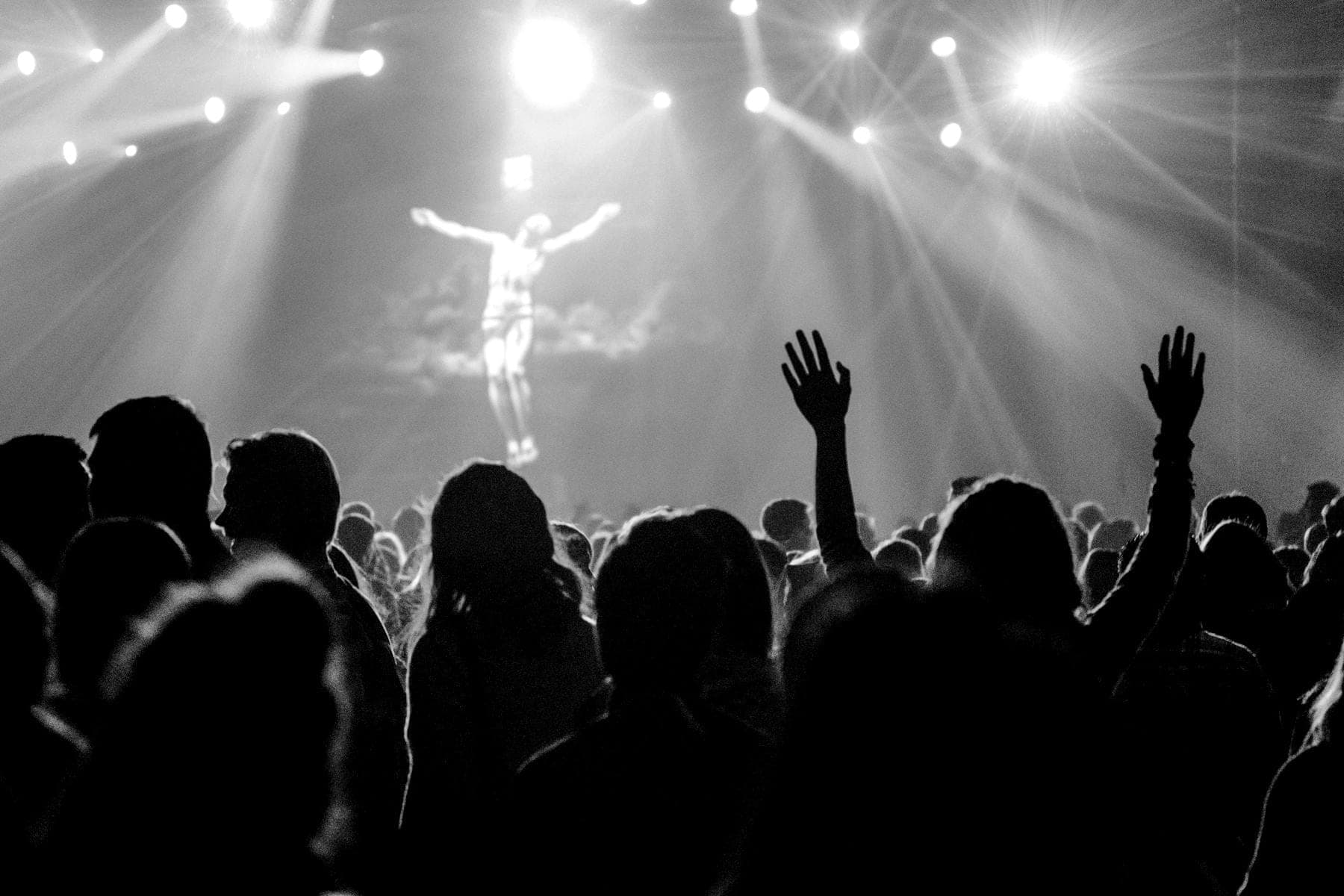 Public de concert, bras levés, face à un artiste sous les projecteurs