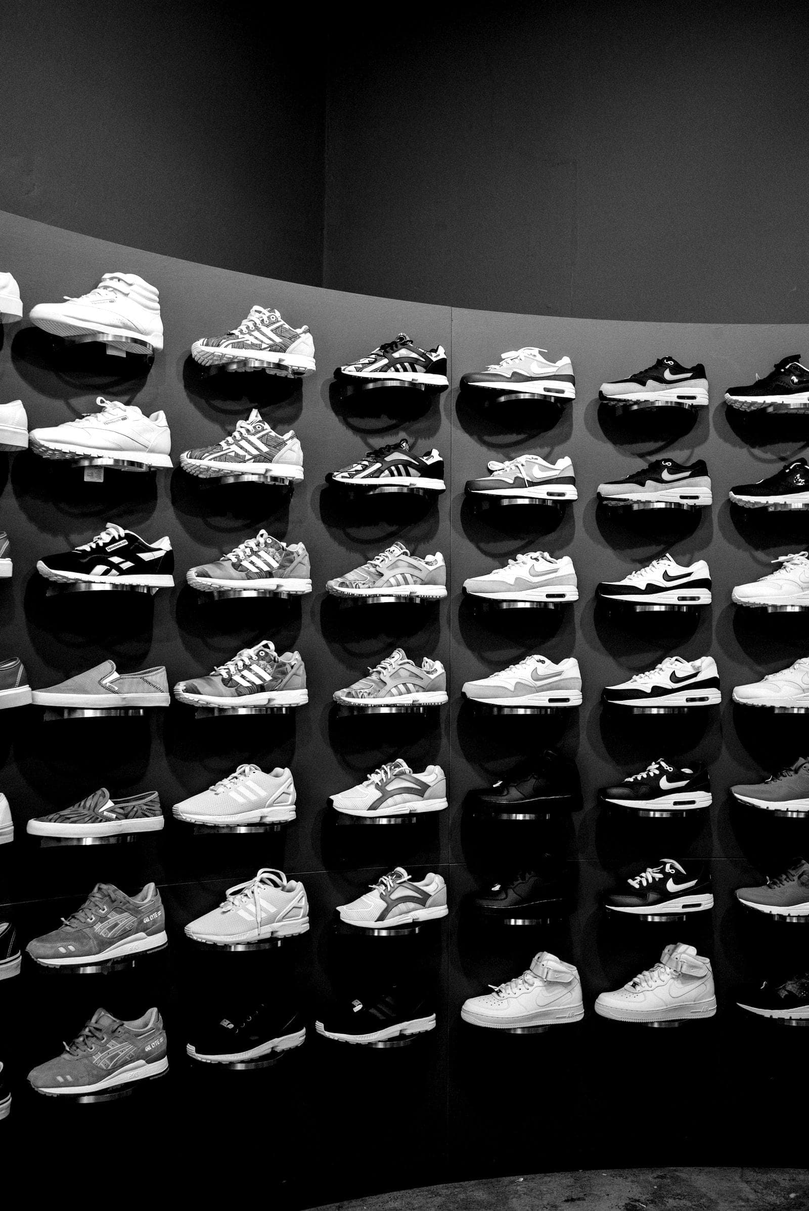 Mur de sneakers exposées dans une boutique plongée dans la pénombre